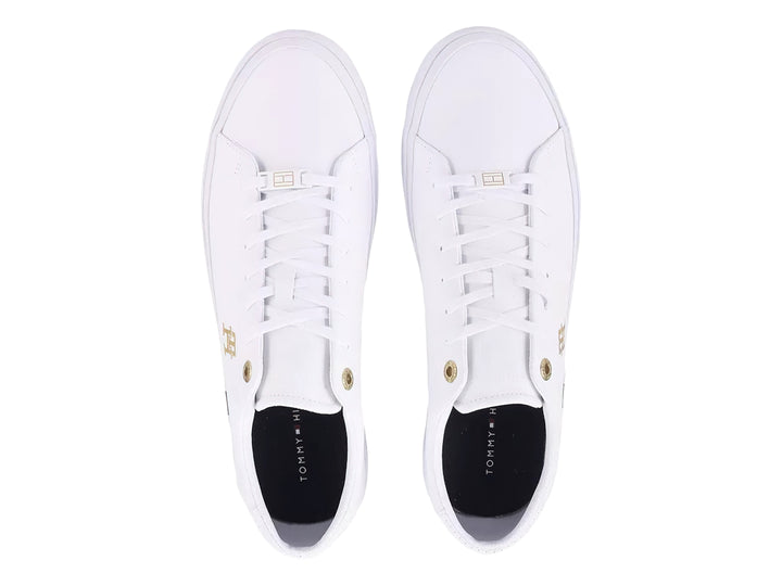 Tenis blancos Tommy Hilfiger de perfil bajo con detalles en dorado y franja roja, blanca y azul en la suela.