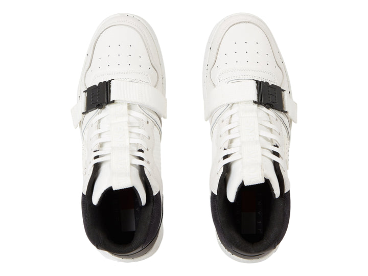 Tenis Tommy Hilfiger color blanco y negro con correa de hebilla y suela blanca moteada.