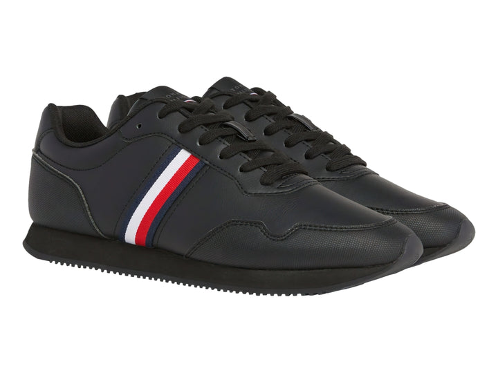 Tenis deportivos color negro con franja lateral tricolor en rojo, blanco y azul.