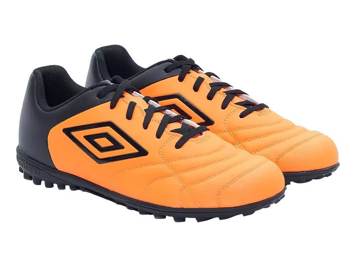 Zapato de fútbol Umbro color naranja y negro con suela para césped sintético.