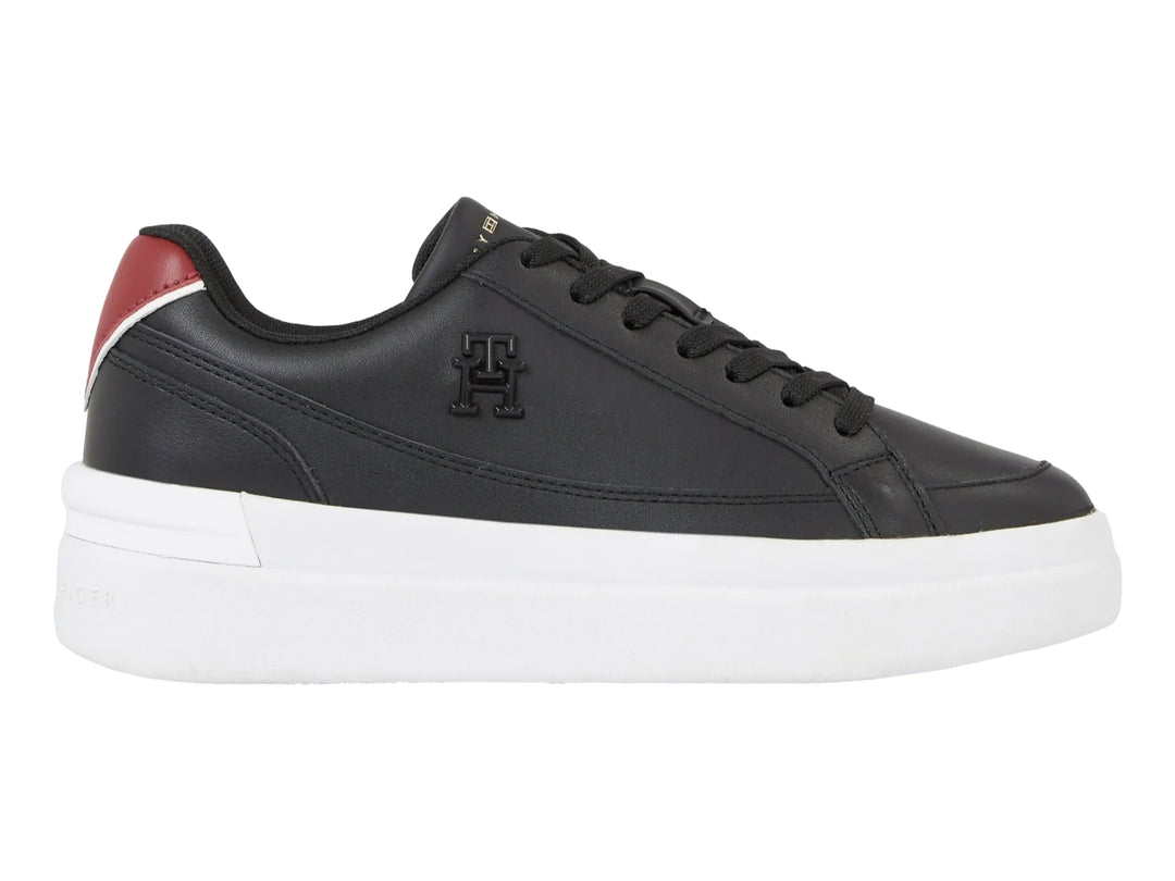 Tenis Tommy Hilfiger color negro con suela blanca ancha y detalle rojo en el talón.