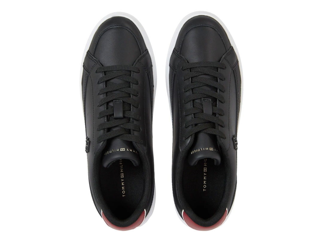 Tenis Tommy Hilfiger color negro con suela blanca ancha y detalle rojo en el talón.