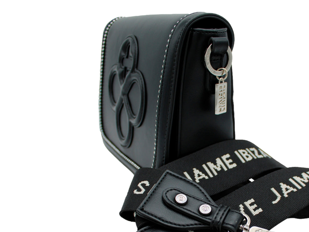 Bolsa negra con correa de cadena plateada y detalle decorativo en relieve frontal.