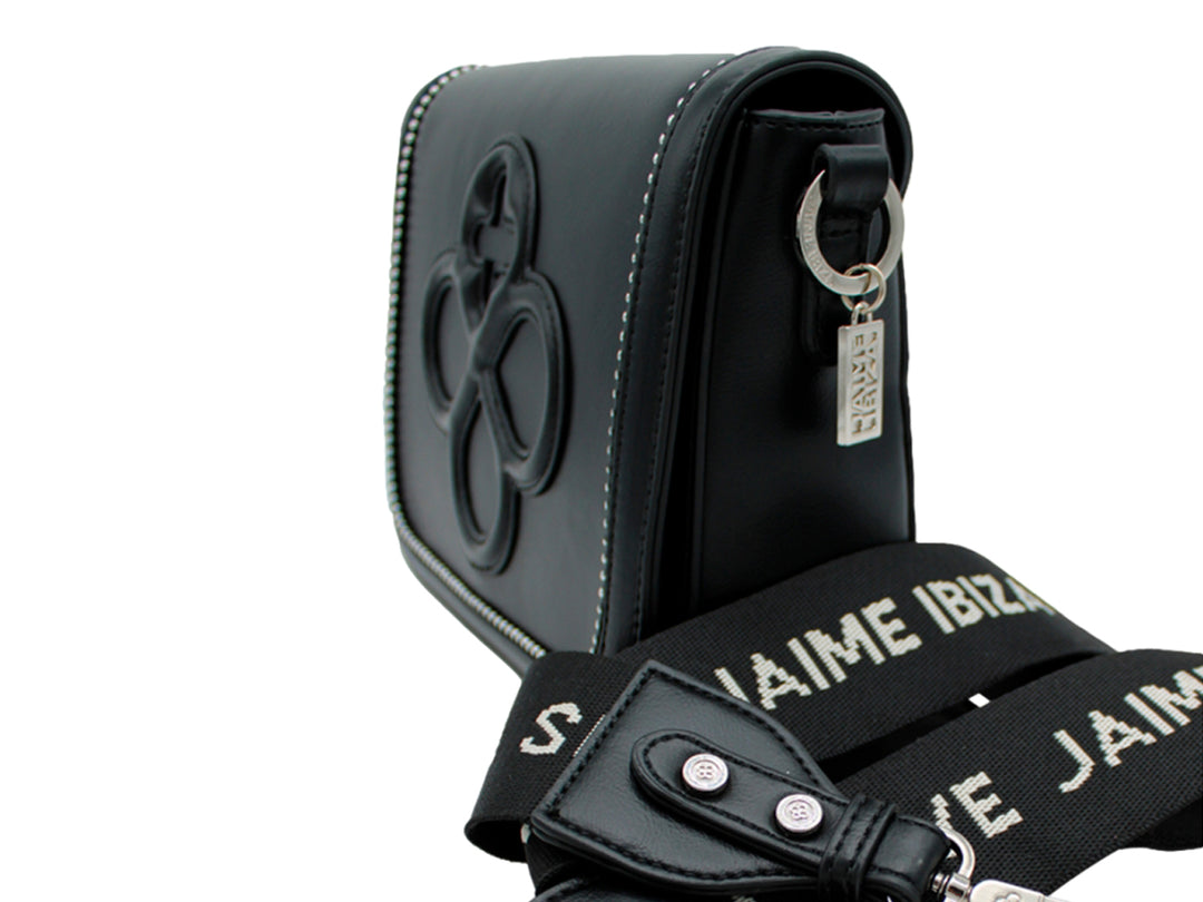 Bolsa negra con correa de cadena plateada y detalle decorativo en relieve frontal.