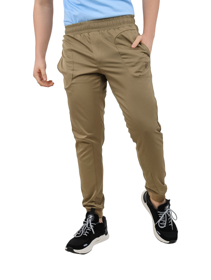 Hombre vistiendo pantalones deportivos K-Swiss color arena con cintura elástica y corte ajustado.