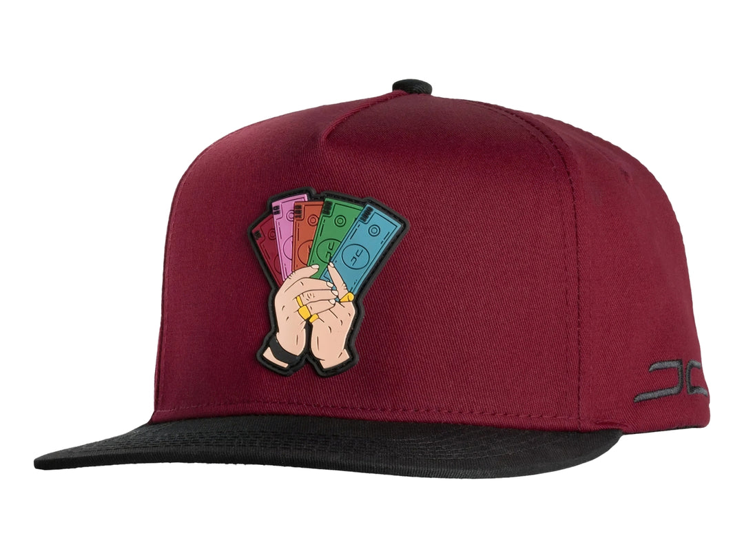 Gorra snapback color rojo con visera negra y un parche bordado frontal de manos sosteniendo billetes.