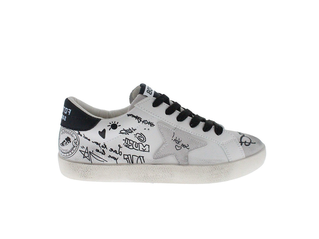 Tenis blancos con cordones negros y dibujos estilo graffiti en los laterales.