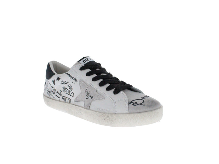 Tenis blancos con cordones negros y dibujos estilo graffiti en los laterales.