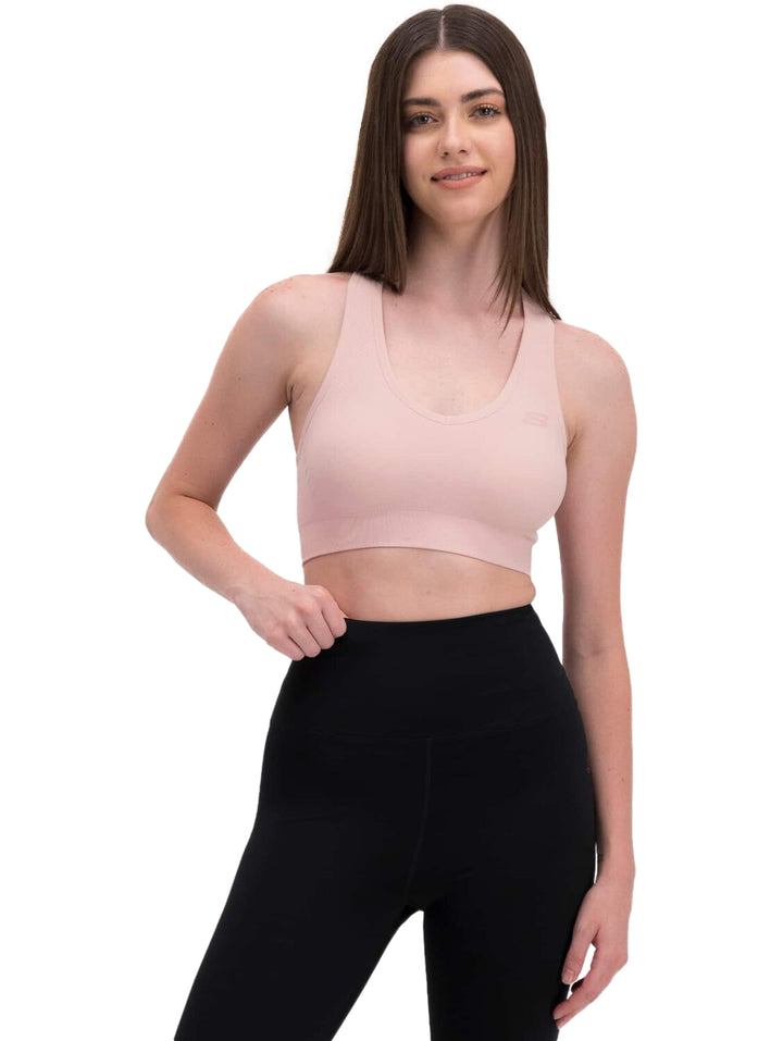 Mujer vistiendo un top deportivo corto de color rosa claro.