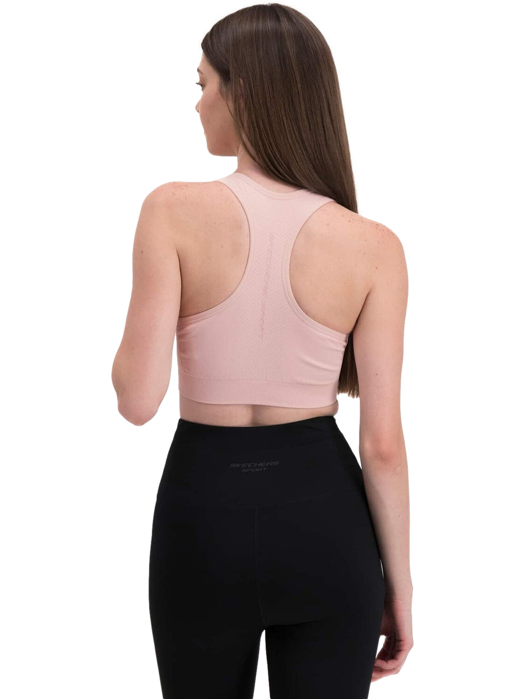 Mujer vistiendo un top deportivo corto de color rosa claro.