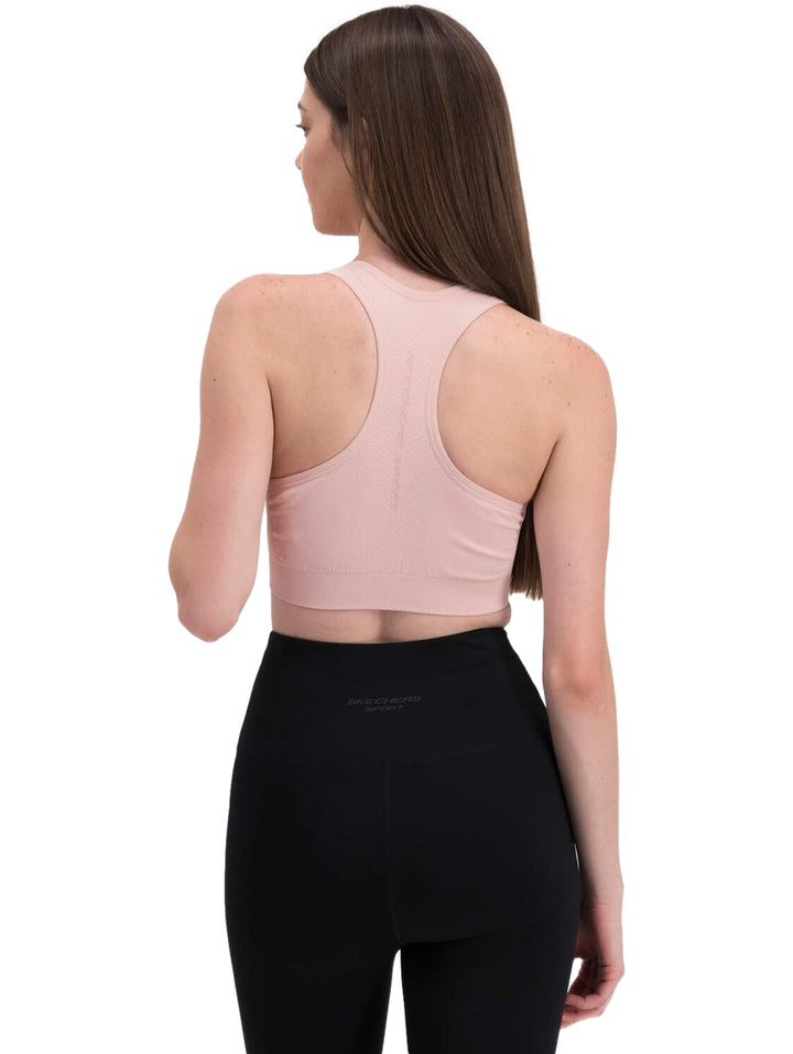 Mujer vistiendo un top deportivo corto de color rosa claro.