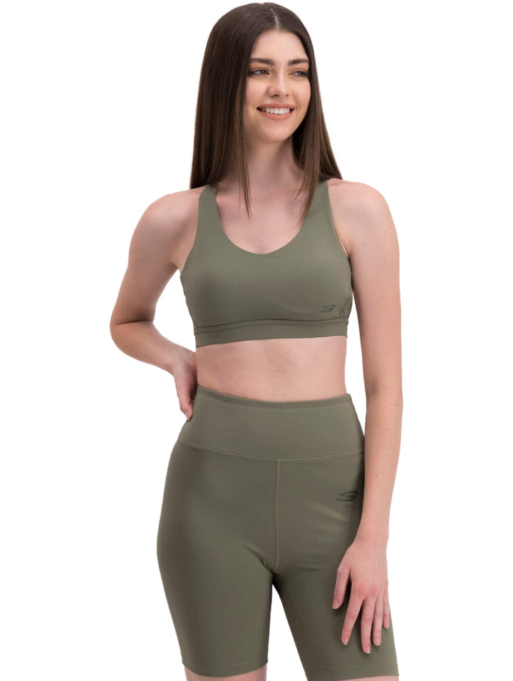 Mujer vistiendo un conjunto deportivo de color verde oliva compuesto por un top corto y shorts ajustados de Skechers.