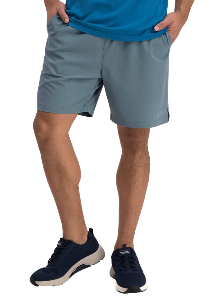 Hombre vistiendo un short deportivo de color azul oscuro marca Skechers con calzado deportivo a juego.