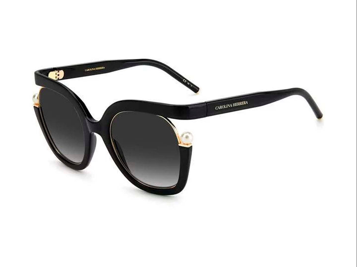 Lentes de sol Carolina Herrera negros con montura ancha, cristales degradados y detalles laterales en dorado.