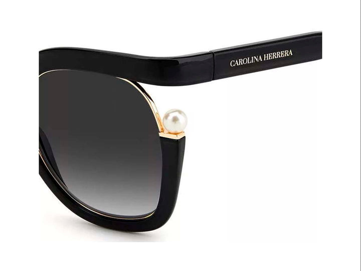 Lentes de sol Carolina Herrera negros con montura ancha, cristales degradados y detalles laterales en dorado.