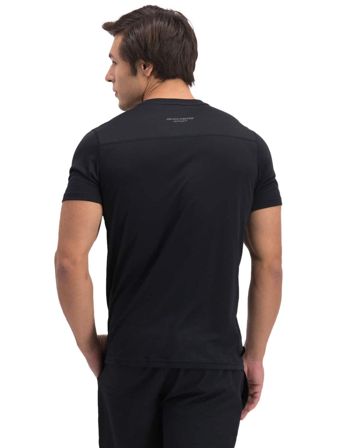 Hombre vistiendo una playera deportiva de color negro de manga corta marca Skechers.