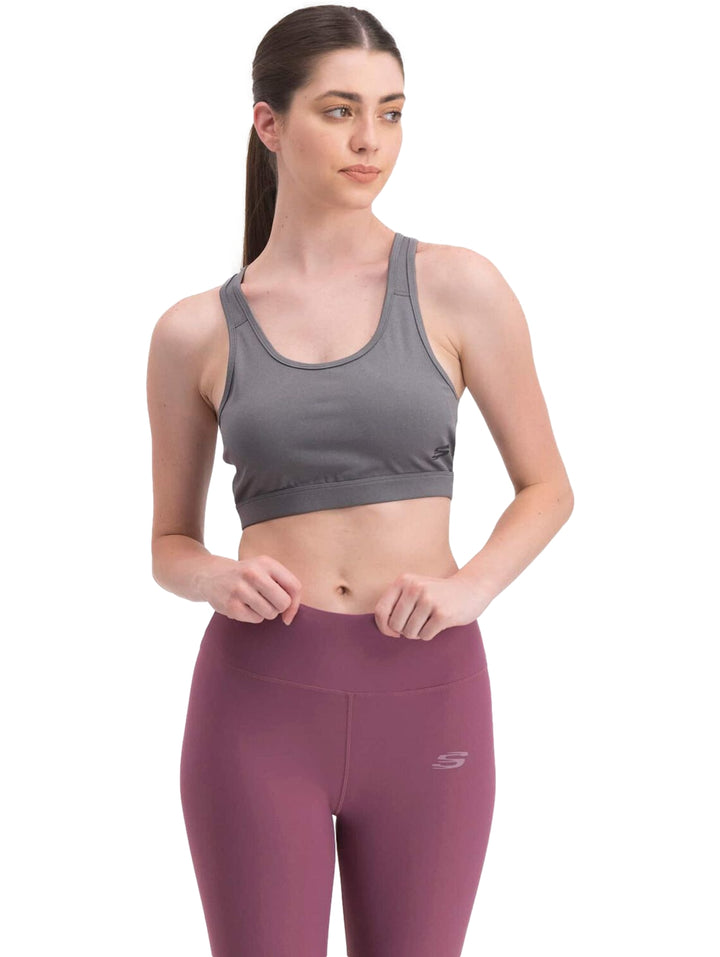 Mujer vistiendo un top deportivo color gris de la marca Skechers.