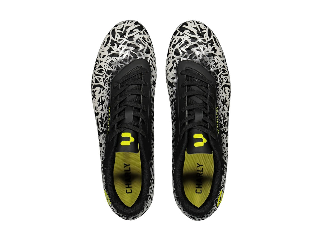 Zapato de fútbol Charly con diseño de graffiti en blanco y negro y detalles en amarillo fluorescente.