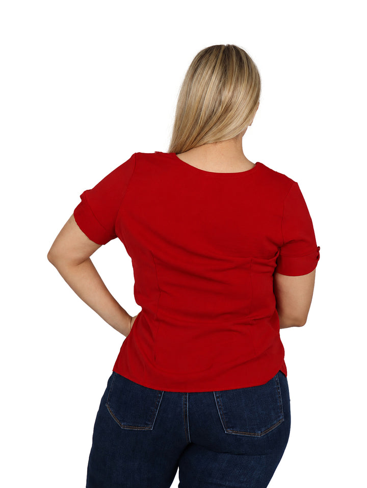 Mujer vistiendo blusa color rojo de manga corta con detalles decorativos en el cuello y el borde inferior.