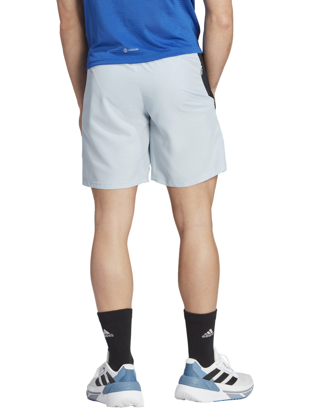 Hombre vistiendo shorts deportivos Adidas color azul claro con franjas negras laterales.