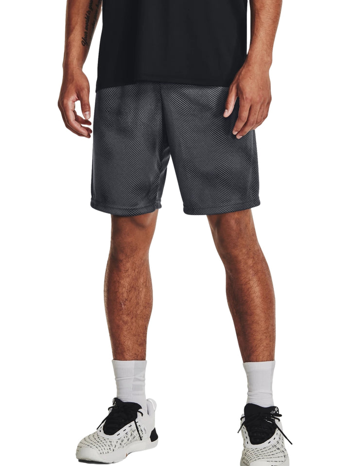 Hombre usando shorts deportivos Under Armour color gris oscuro y negro con diseño de rayas diagonales.
