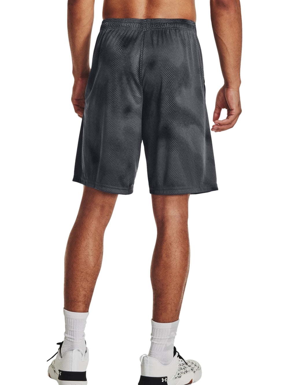 Hombre usando shorts deportivos Under Armour color gris oscuro y negro con diseño de rayas diagonales.