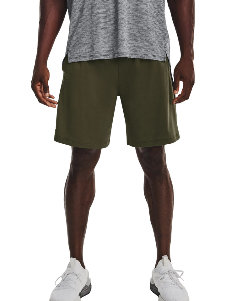 Hombre vistiendo pantalones cortos deportivos Under Armour en color verde oliva oscuro.