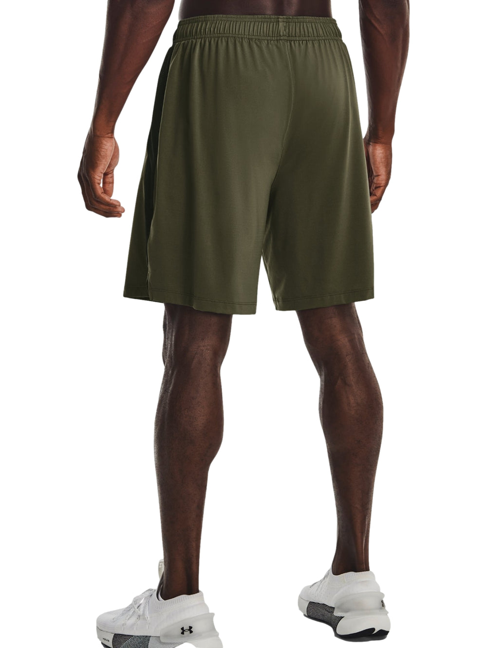 Hombre vistiendo pantalones cortos deportivos Under Armour en color verde oliva oscuro.