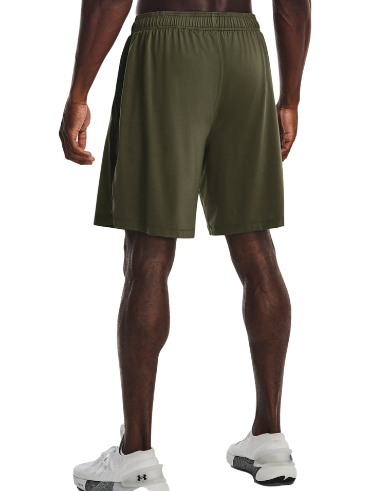 Hombre vistiendo pantalones cortos deportivos Under Armour en color verde oliva oscuro.