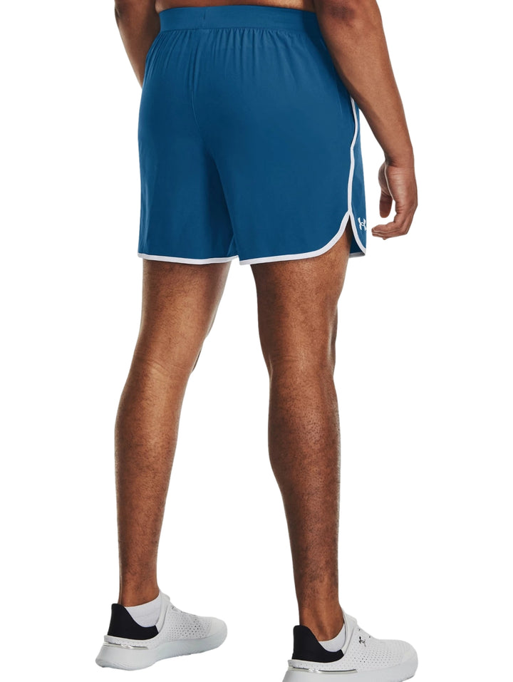 Hombre vistiendo shorts deportivos color azul con ribete blanco de la marca Under Armour.