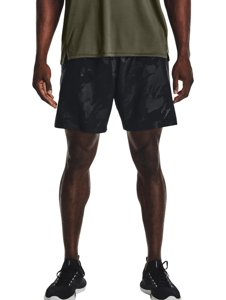 Hombre vistiendo shorts deportivos negros con un patrón grabado sutil de la marca Under Armour.