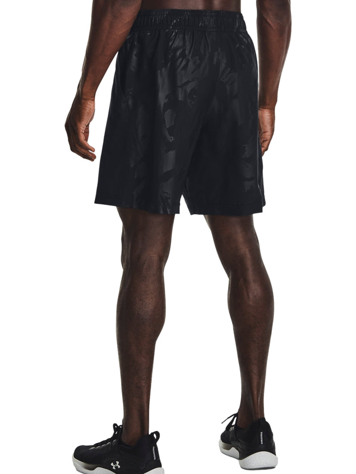Hombre vistiendo shorts deportivos negros con un patrón grabado sutil de la marca Under Armour.