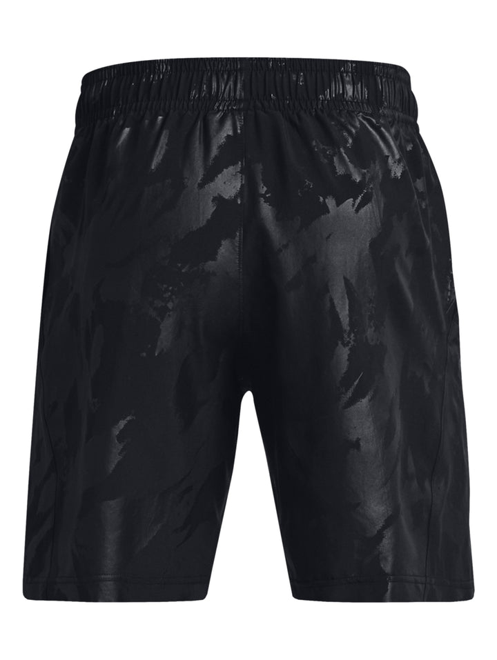 Hombre vistiendo shorts deportivos negros con un patrón grabado sutil de la marca Under Armour.