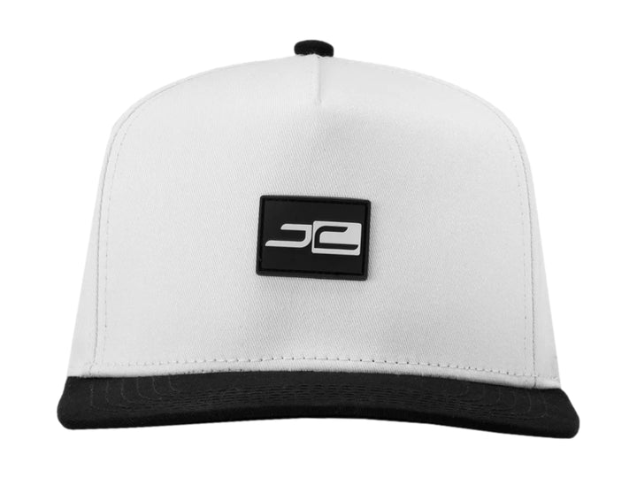 Gorra snapback blanca con visera plana negra y logotipos JC en contraste.