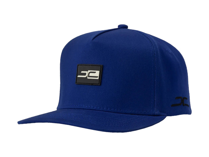 Gorra snapback de color azul con visera plana y logotipo JC en el frente y lateral.