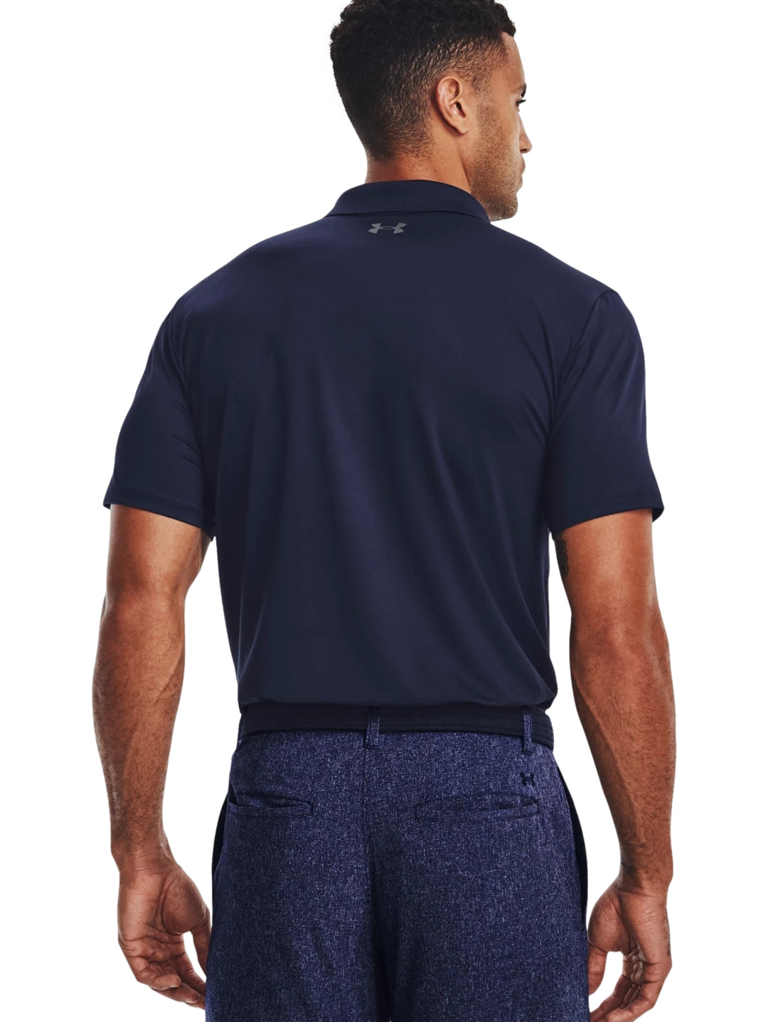 Hombre vistiendo una playera polo Under Armour de color azul marino con logotipo en el pecho.