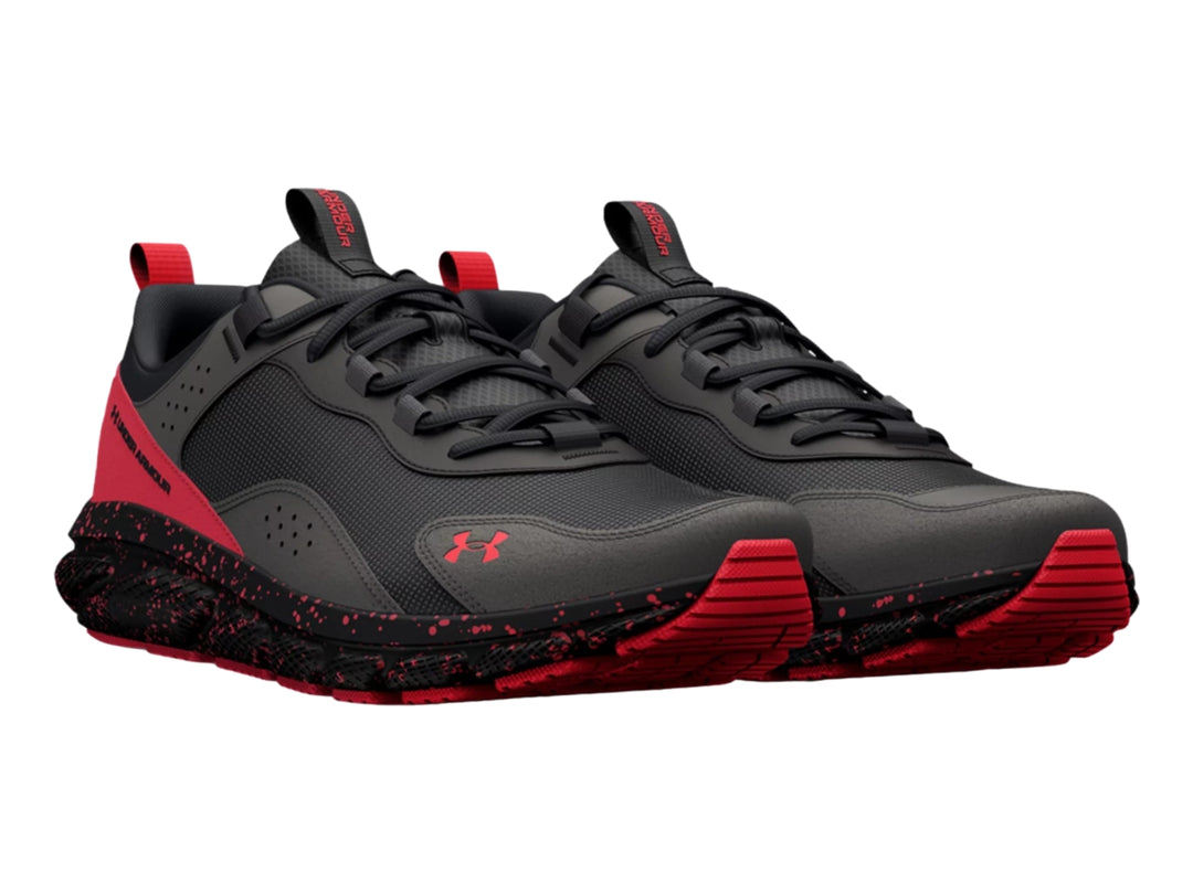 Tenis deportivos Under Armour en color gris con detalles y suela moteada en color rojo.