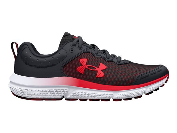 Tenis deportivo Under Armour para niños en color negro con detalles rojos y suela blanca y roja.