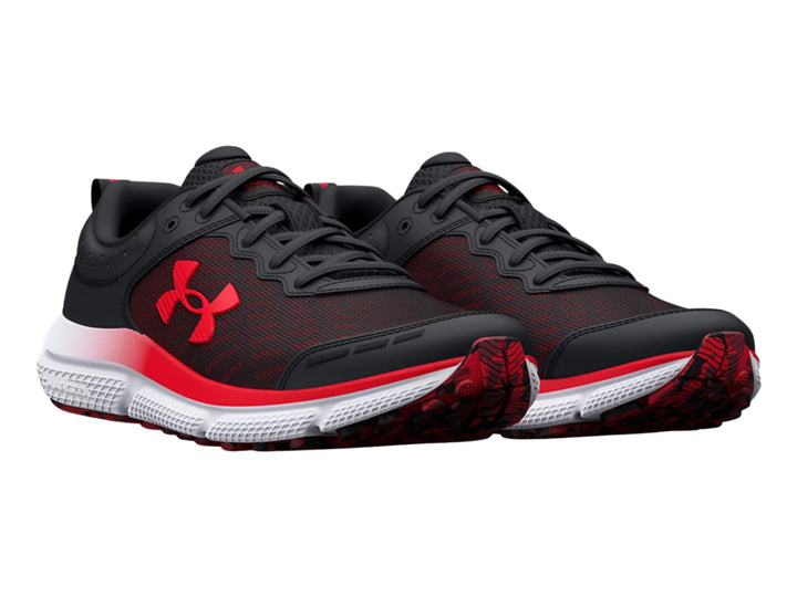 Tenis deportivo Under Armour para niños en color negro con detalles rojos y suela blanca y roja.
