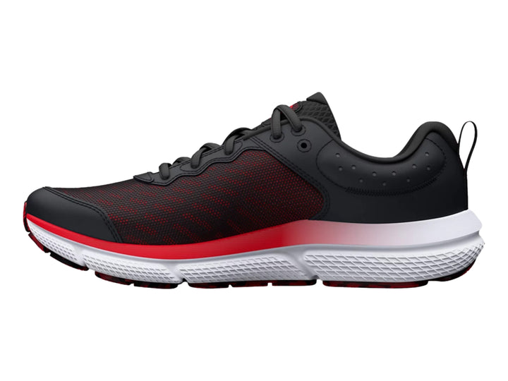 Tenis deportivo Under Armour para niños en color negro con detalles rojos y suela blanca y roja.