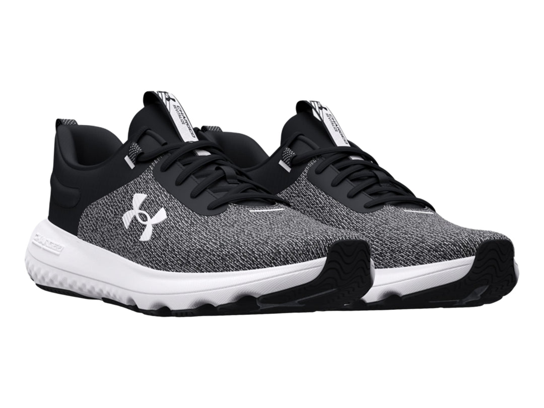 Tenis deportivos Under Armour en color negro y blanco con suela blanca y tejido transpirable.