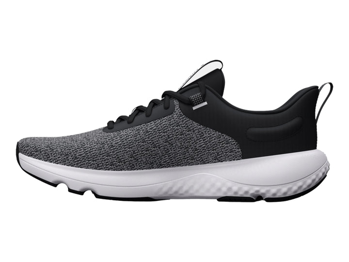Tenis deportivos Under Armour en color negro y blanco con suela blanca y tejido transpirable.