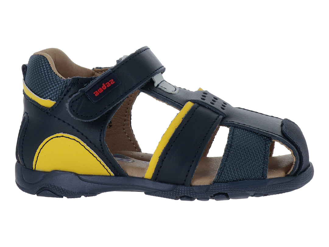 Sandalia infantil cerrada color azul marino con detalles amarillos y cierre de velcro.