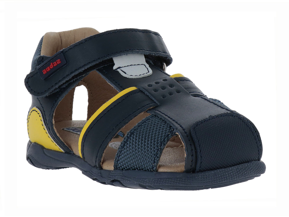 Sandalia infantil cerrada color azul marino con detalles amarillos y cierre de velcro.