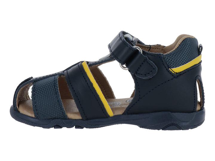 Sandalia infantil cerrada color azul marino con detalles amarillos y cierre de velcro.