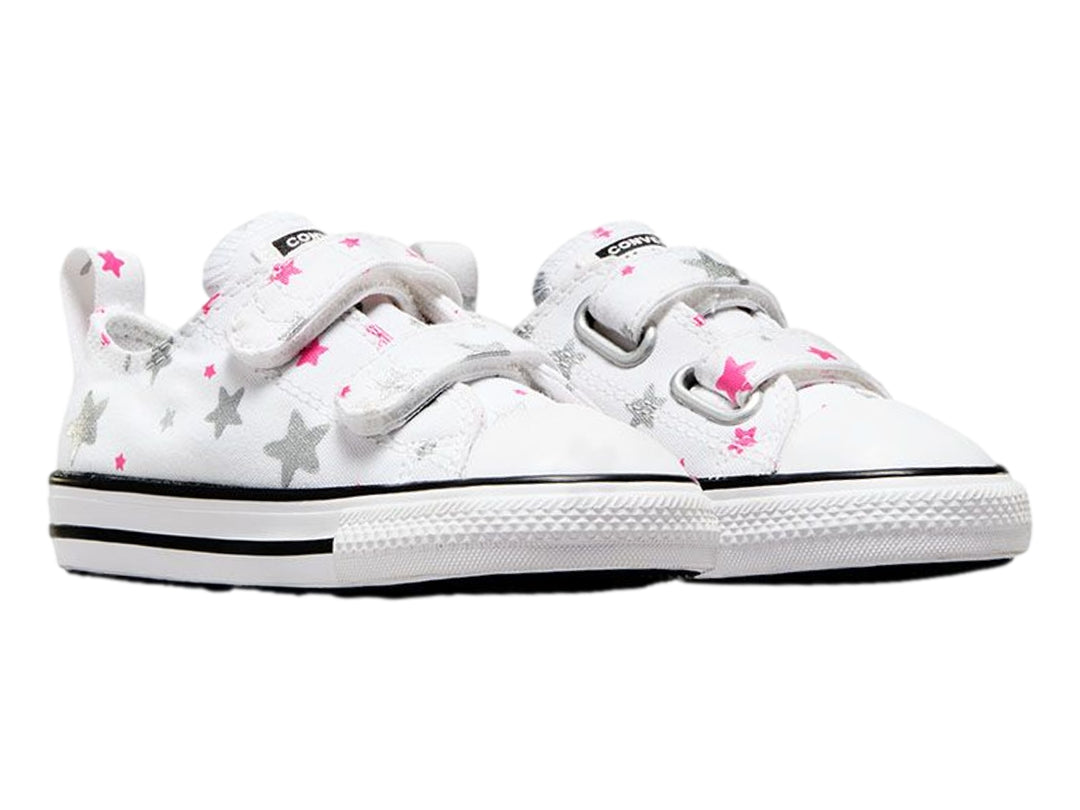 Tenis Converse blancos para niño o niña con estampado de estrellas grises y rosas, cierre de velcro y suela blanca.