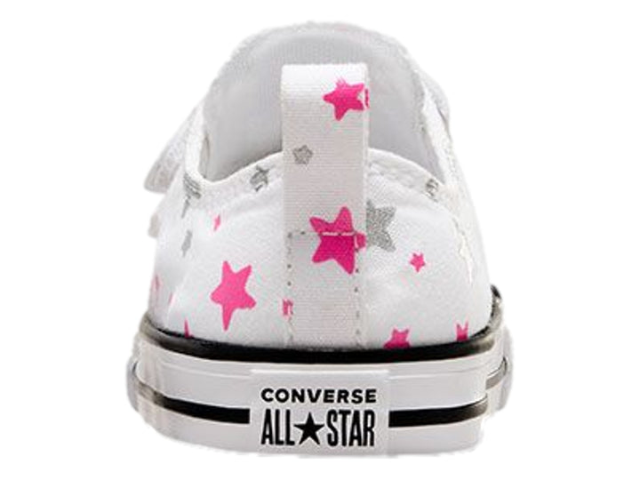 Tenis Converse blancos para niño o niña con estampado de estrellas grises y rosas, cierre de velcro y suela blanca.