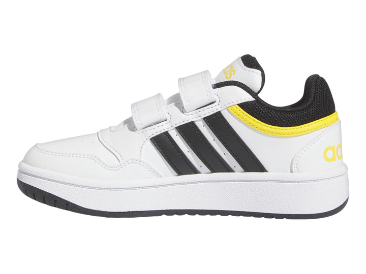 Tenis Adidas blancos con tres franjas negras, detalles amarillos y cierre de velcro.