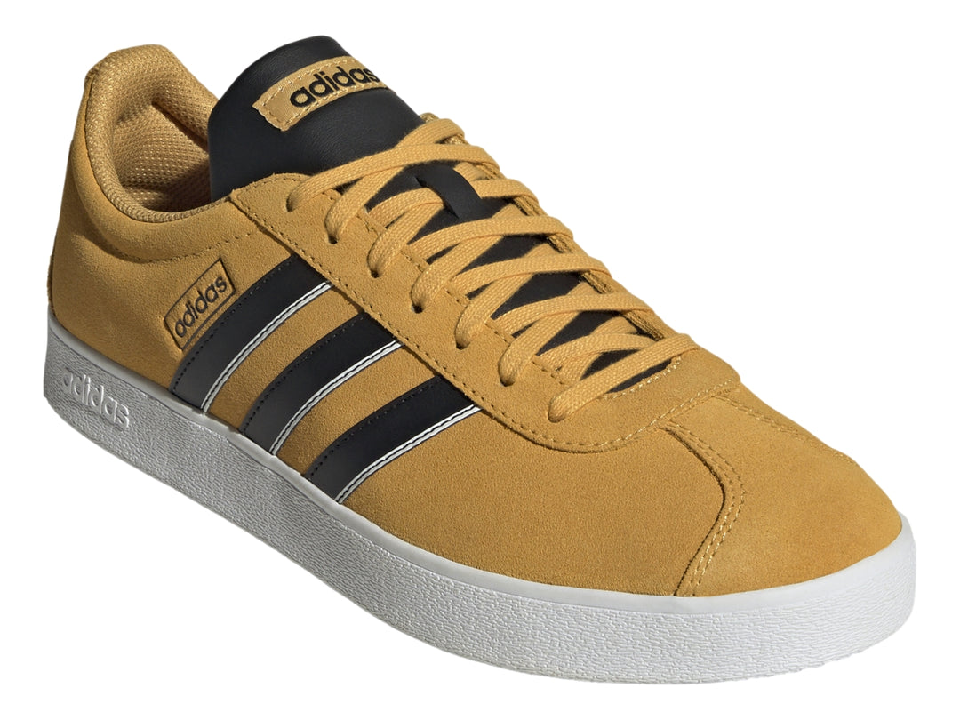 Tenis Adidas VL Court Classic color café mostaza con tres franjas negras y suela blanca.