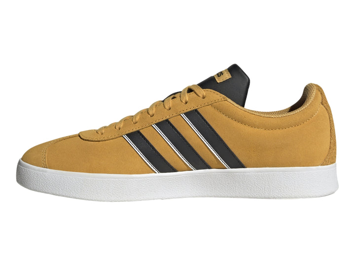 Tenis Adidas VL Court Classic color café mostaza con tres franjas negras y suela blanca.